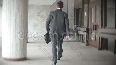商人一边走一边提着公文包。 穿正装的男士在现代<strong>办公大楼</strong>附近散步